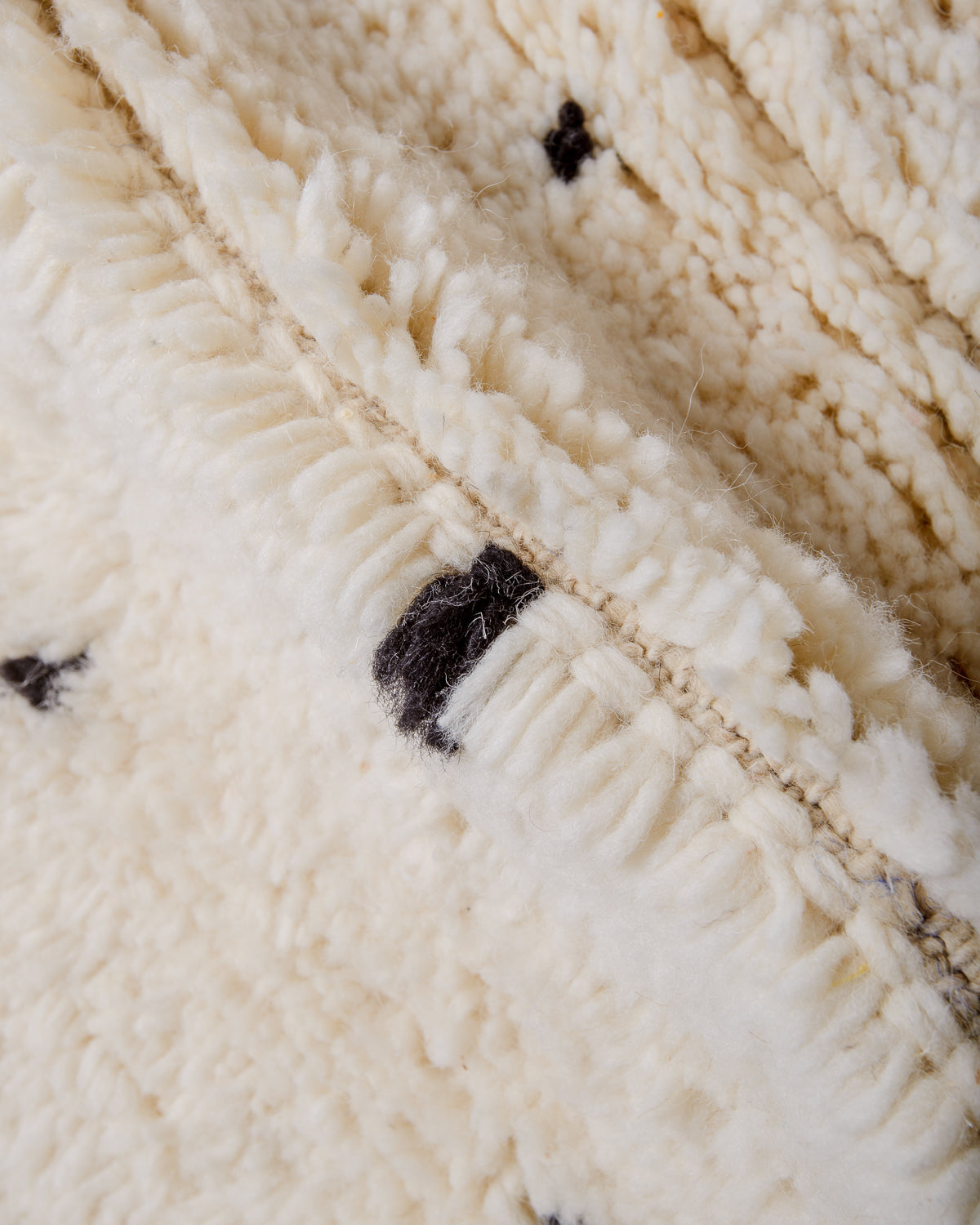 Close up of wool knots on rug in cream and black.